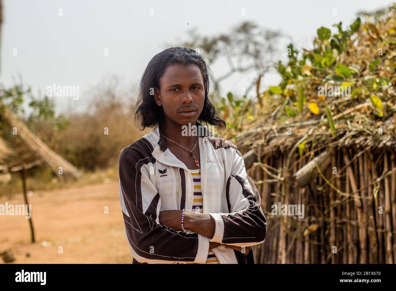 Un ragazzo di Hausa/Fulani posa per la foto di fronte a una casa di paglia in un villaggio di Abuja, Nigeria. Foto Stock