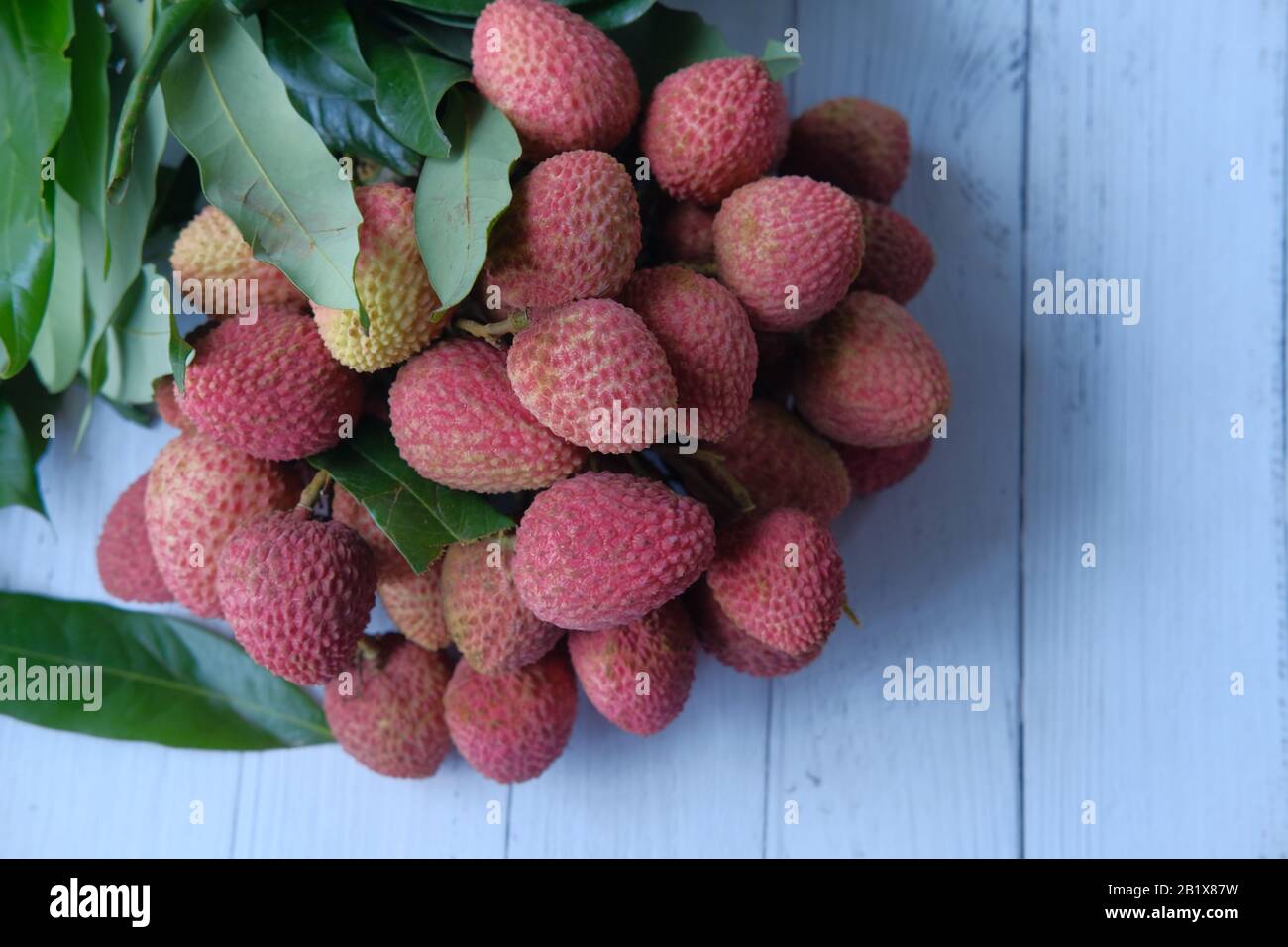 Lychee fresco con foglie su sfondo di legno frutta tropicale Foto Stock