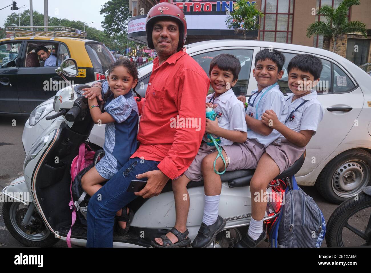 Cinque su uno scooter: Un padre allegro a Mumbai (Bombay), India, ferrying suo figlio e tre compagni di scuola a casa dalla scuola sul suo scooter a motore Foto Stock