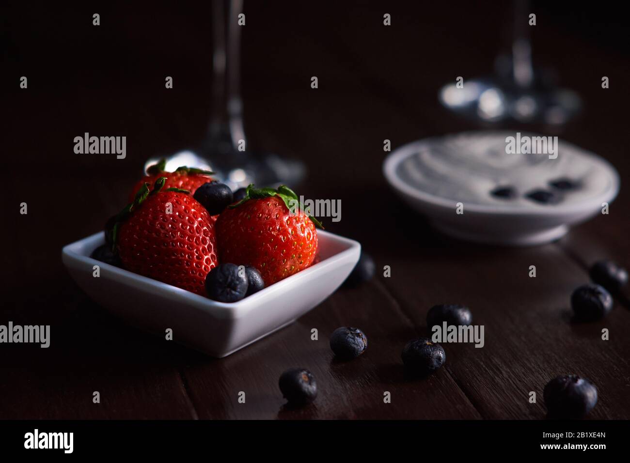 Fragole e mirtilli su tazza di ceramica e crema chantilly in tazza di ceramica su fondo di legno marrone Foto Stock
