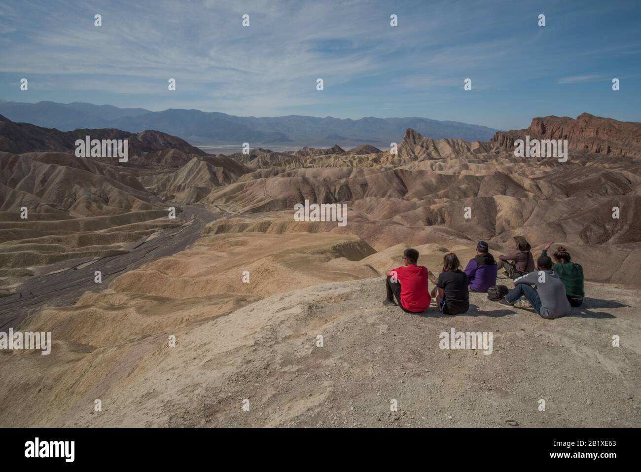 Un gruppo di visitatori del Death Valley National Park in California si siedono a un punto panoramico e si affacciano sull'impressionante paesaggio nel deserto. Foto Stock