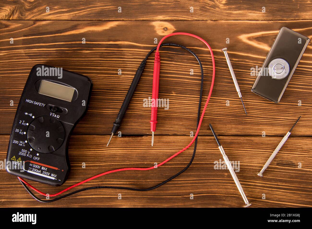 Set per saldatura filo e tubo di saldatura termoretraibile con saldatura accanto a cacciavite e multimetro su sfondo in legno, concetto di elettronica radio Foto Stock