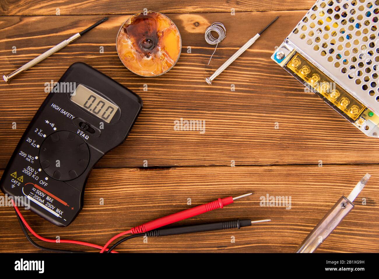 Set per saldatura filo e tubo di saldatura termoretraibile con saldatura accanto a cacciavite e multimetro su sfondo in legno, concetto di elettronica radio Foto Stock