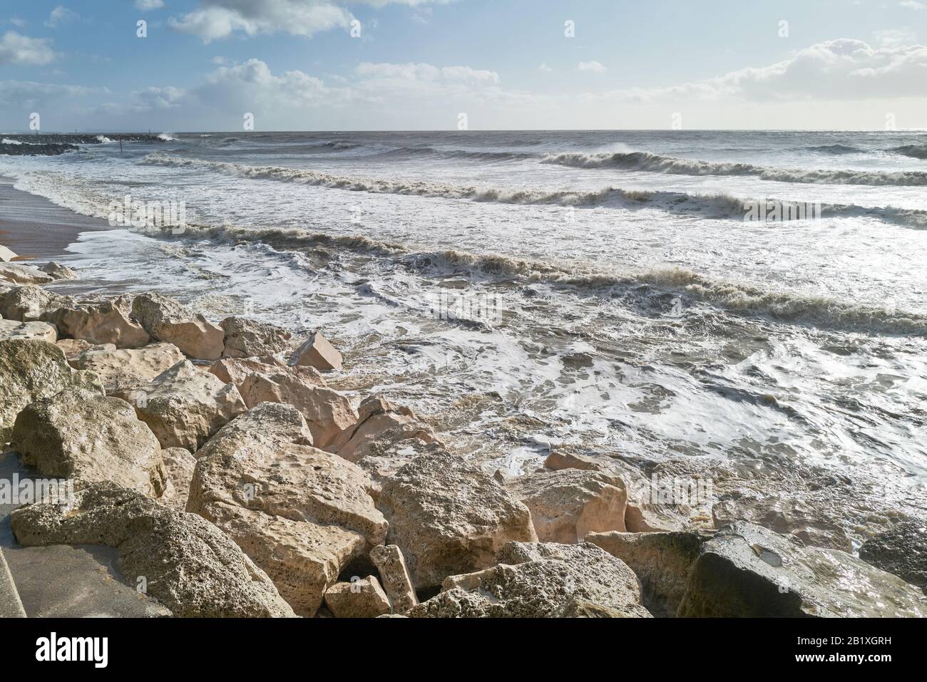 Rocce di difesa del mare bianche sbiancate dalle onde durante il tempo invernale tempestoso lungo la linea costiera del patrimonio giurassico del mare della Manica a West Bay, Foto Stock