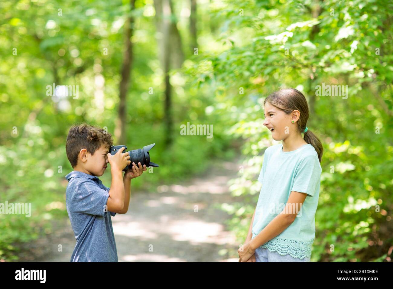 Ragazzo giovane che scatta una foto della sorella nella foresta. Foto Stock