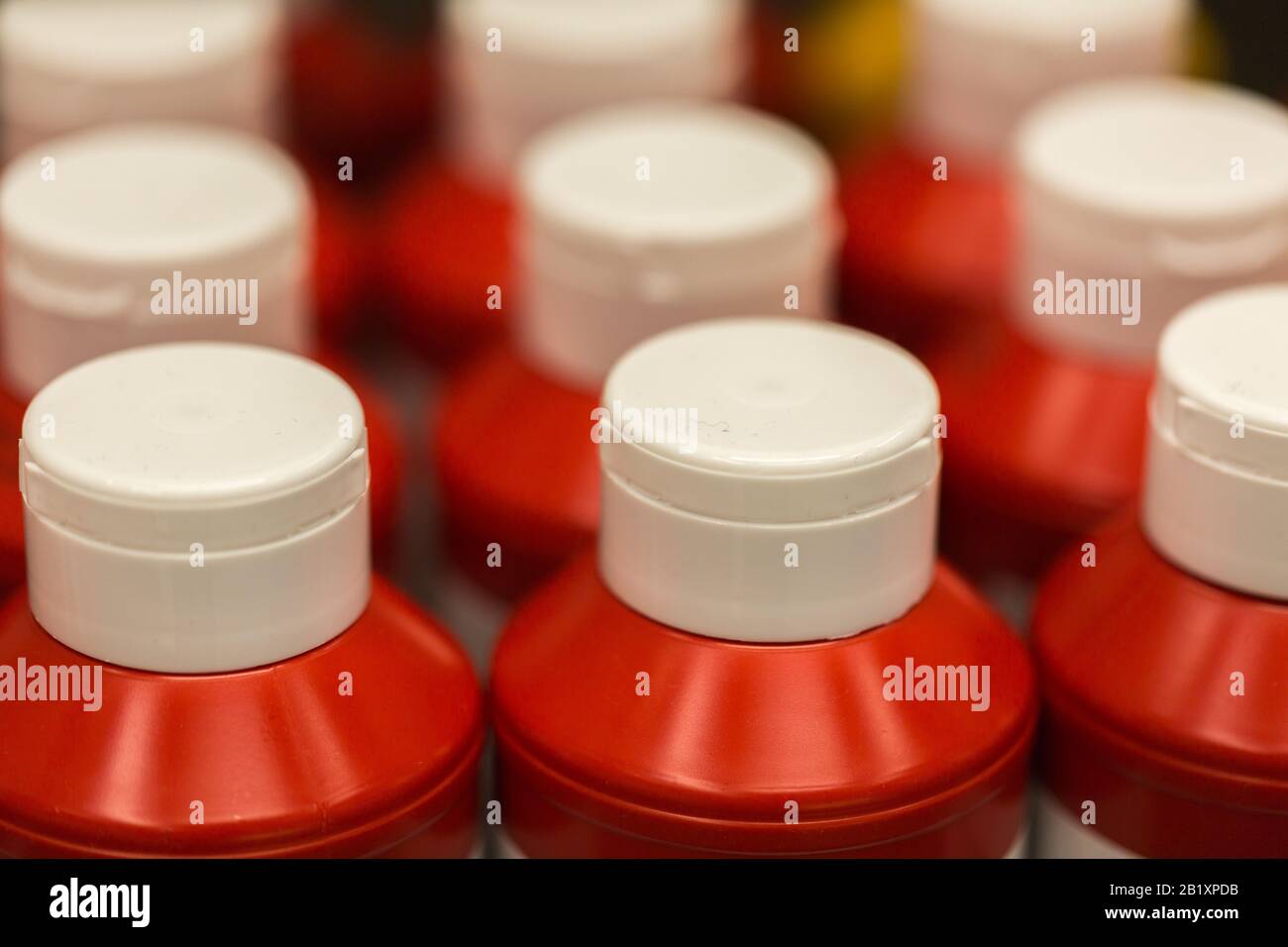 Primo piano / macro di bottiglie di plastica con tappo bianco e corpo rosso. Le bottiglie contengono ketchup. Foto Stock