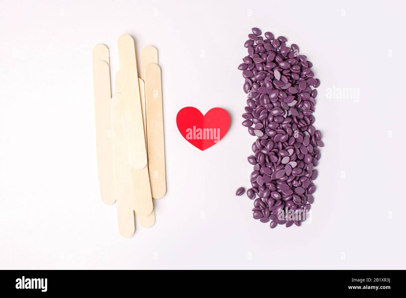 Depilatory Purple Pearl Hard Wax Beans, spatola in legno stick, cuore, concetto di cura del corpo skincare, industria della bellezza, salone termale, hait rimuovere materiale. D Foto Stock