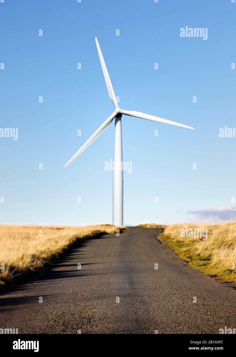 Una turbina eolica alla fine di una strada di campagna Foto Stock