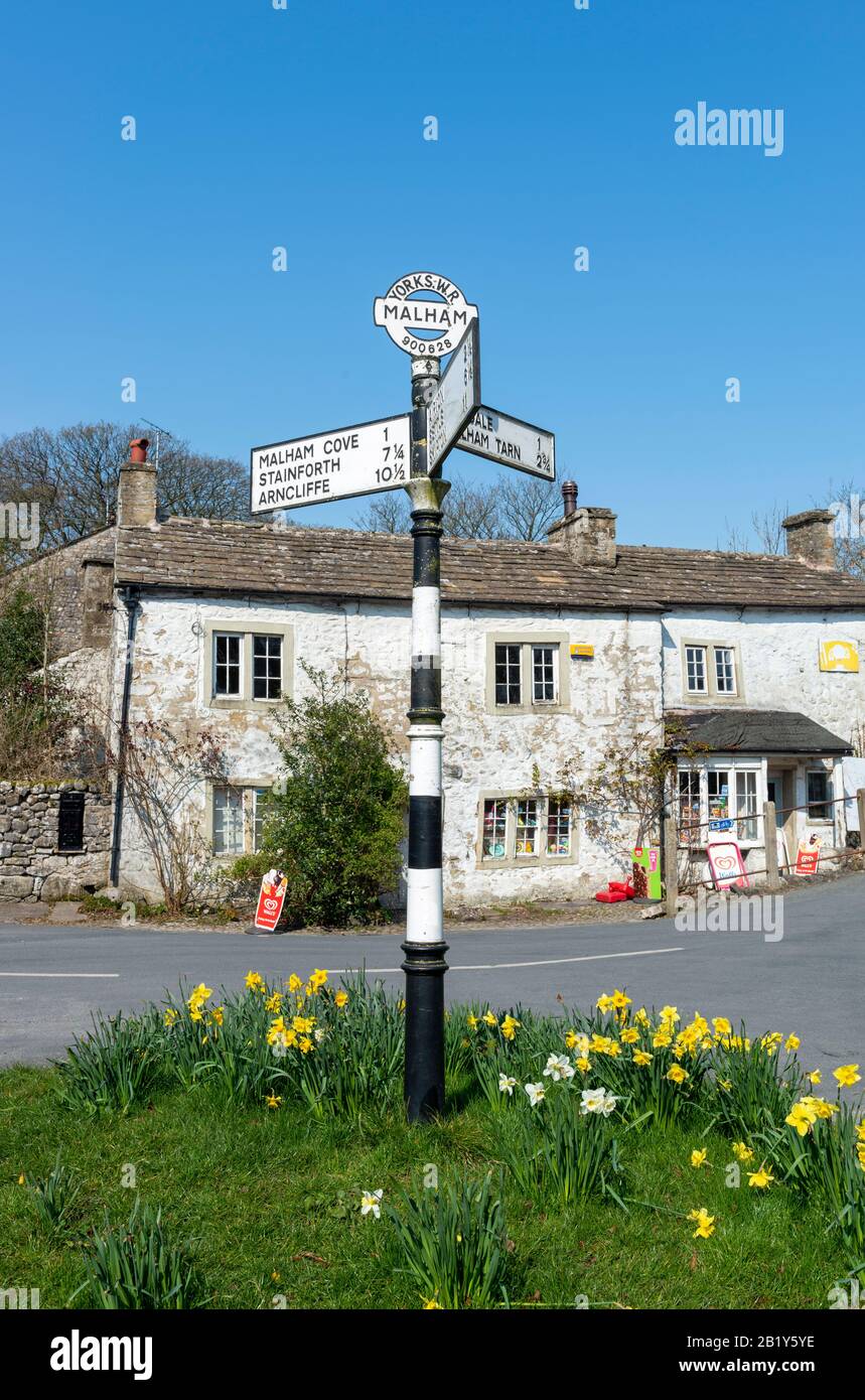 Foto di primavera di un antico cartello stradale bianco e nero nel centro del villaggio di Yorkshire Dales di Malham Foto Stock