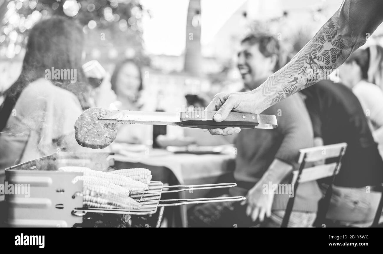 Hamburger da uomo tatuati alla cena barbecue all'aperto - cibo grigliato Chef per barbecue - stile di vita estivo, weekend con concetto di famiglia - Focus o Foto Stock