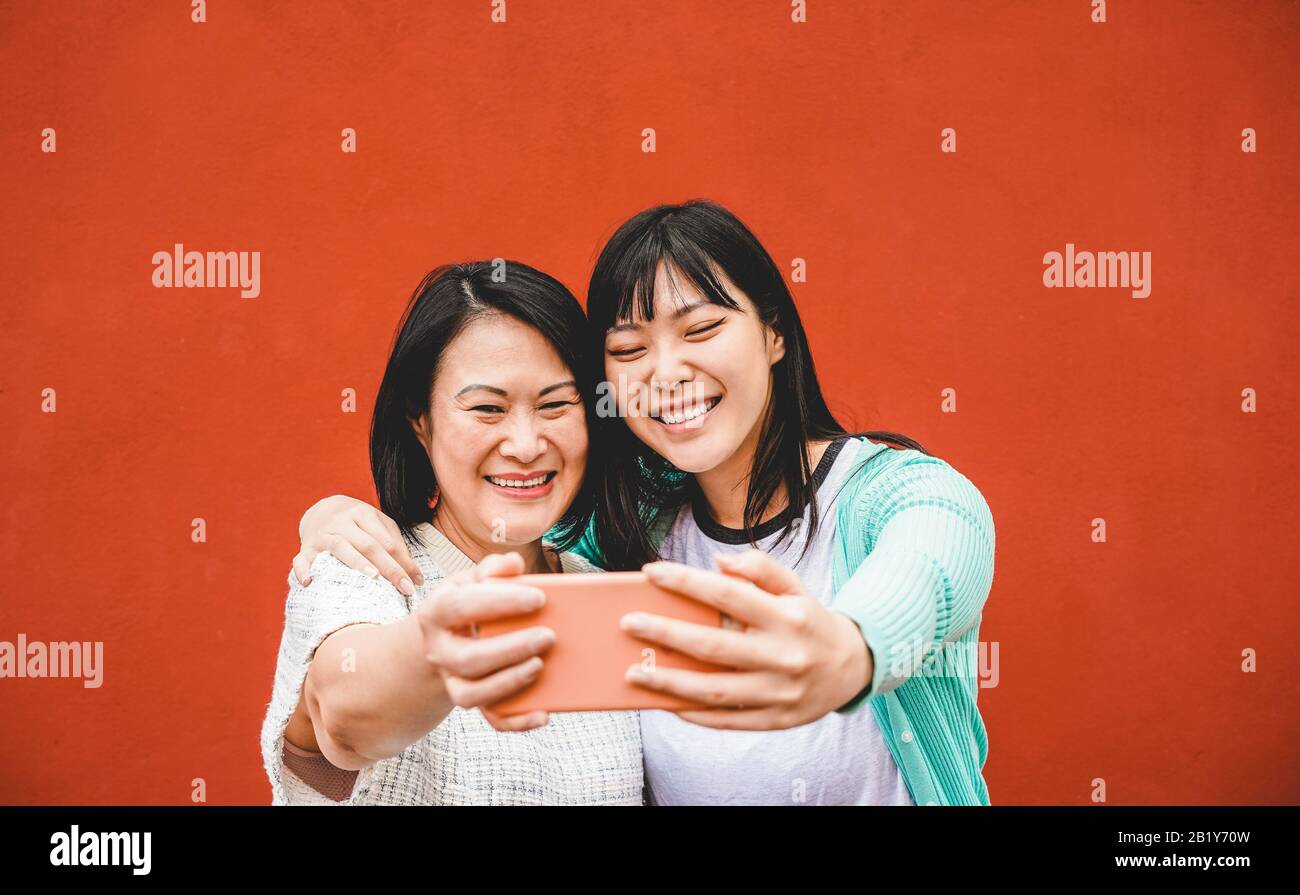 Madre e figlia asiatiche che prendono selfie con smartphone per l'app storia - la gente felice della famiglia che si diverte con le tendenze della tecnologia - Amore, vita genitorialità Foto Stock
