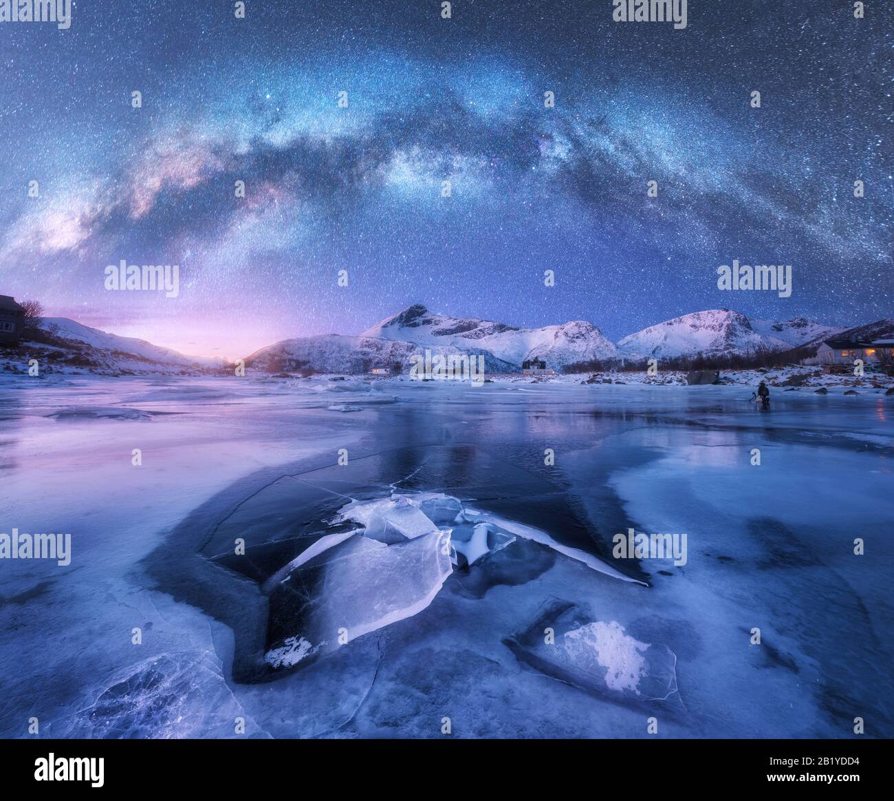 Via Lattea sopra la costa ghiacciata del mare e le montagne innevate Foto Stock