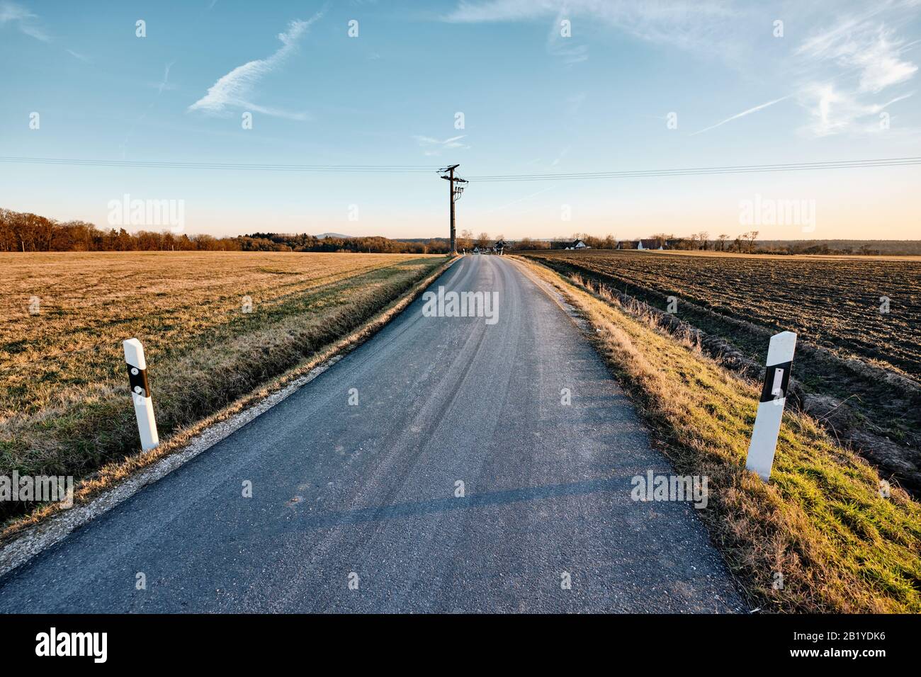 Lunga curva strada di campagna con prospettiva decrescente con posta lungo la luce del tardo pomeriggio. Visto In Franconia / Baviera, Foto Stock