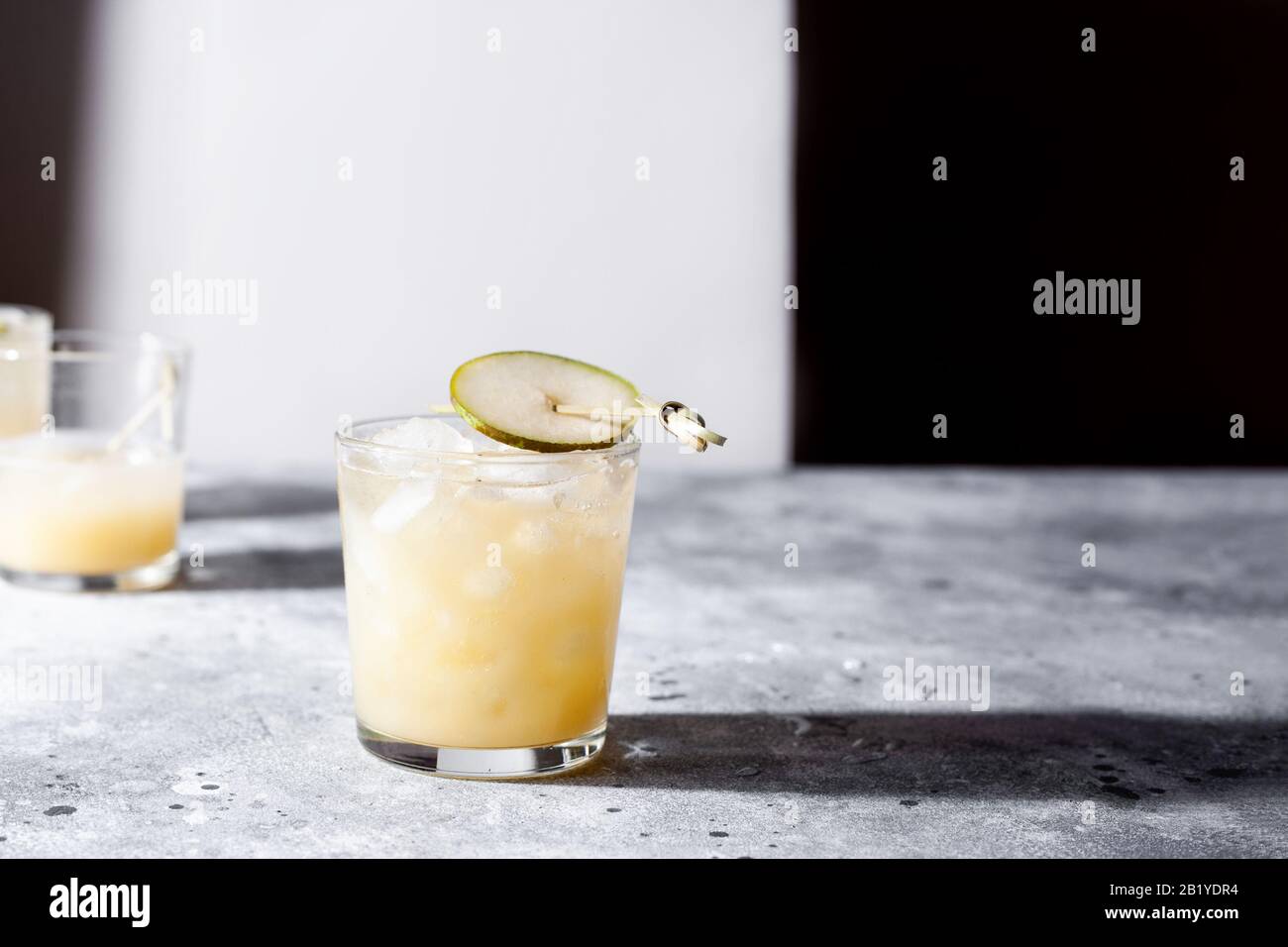 Un bicchiere corto di rinfrescante mocktail di acqua di soda di pera o un cocktail su sfondo grigio cemento. Bevanda estiva non alcolica. Orientamento orizzontale Foto Stock
