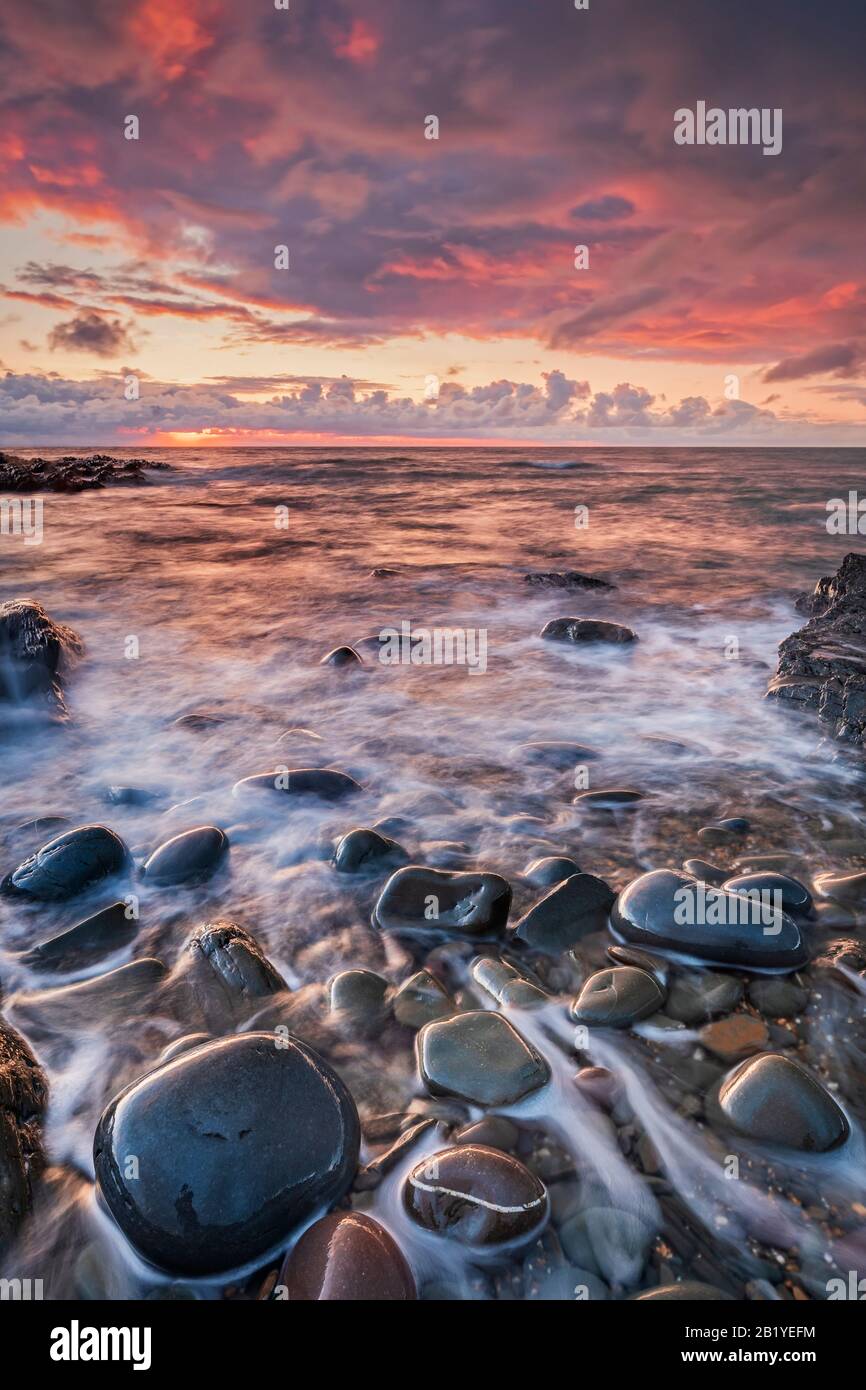Cielo romantico e spettacolare al tramonto sul Devon settentrionale, spiaggia, costa, costa, costiero, costiero, stordimento, costa, rocce, riflessi, ciottoli, nuvole, Regno Unito Foto Stock