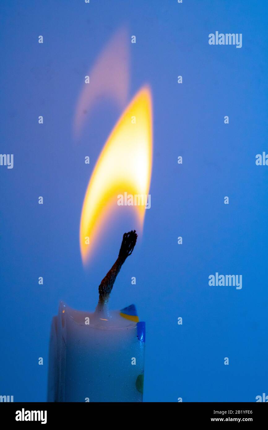 Un primo piano di una singola fiamma candela e un pulcino su sfondo colorato Foto Stock