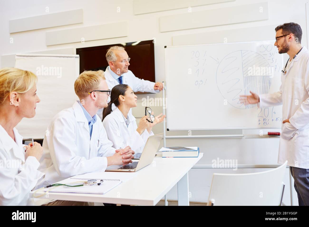 Medici durante una sessione di formazione con un ufficiale farmaceutico sulla lavagna Foto Stock