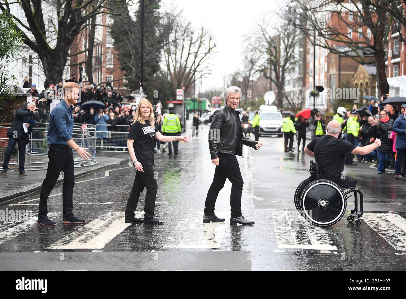 Il Duca del Sussex, Jon Bon Jovi e i membri del Coro Invictus Games camminano sulla famosa zebra attraversando fuori gli Abbey Road Studios di Londra. Foto Stock