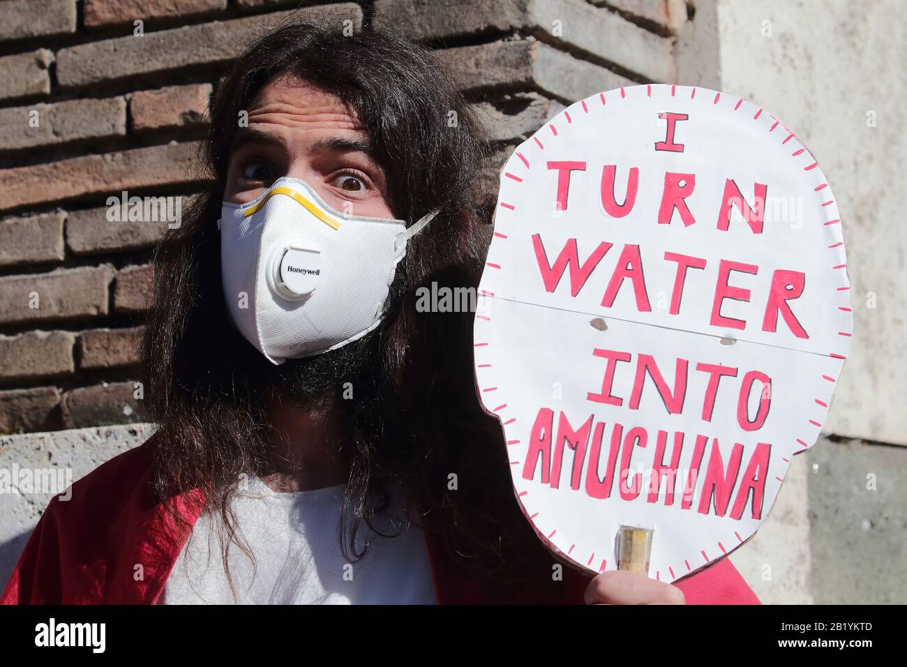 Roma, Italia. 28th Feb 2020. L'artista di strada SIMONE SPIGA vestito come  Jusus Christ dispensa il miracolo per strappare l'acqua in Amuchina. Il  disinfettante Amuchina utilizzato contro il coronavirus spesso non presente