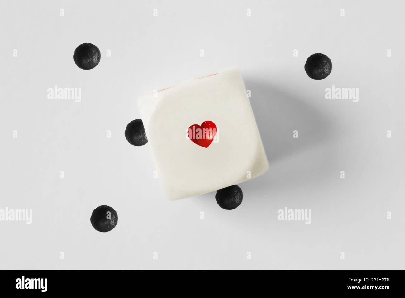 Dadi con cuore e punti neri persi su sfondo bianco Foto Stock