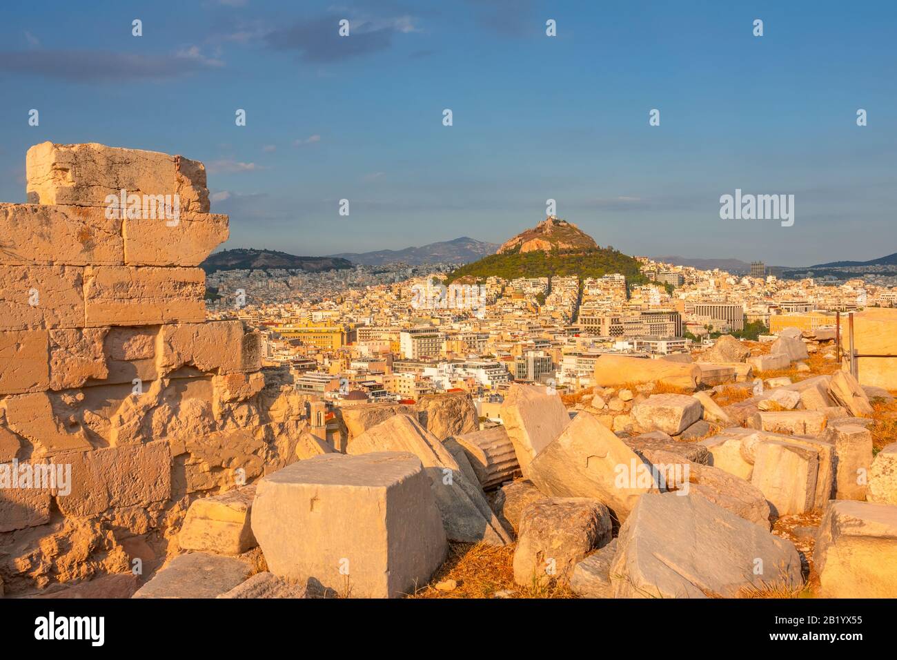 Grecia. Tramonto ad Atene. Rovine di marmo in primo piano. Vista da un punto alto sui tetti della città e sulla collina di Lycabettus Foto Stock