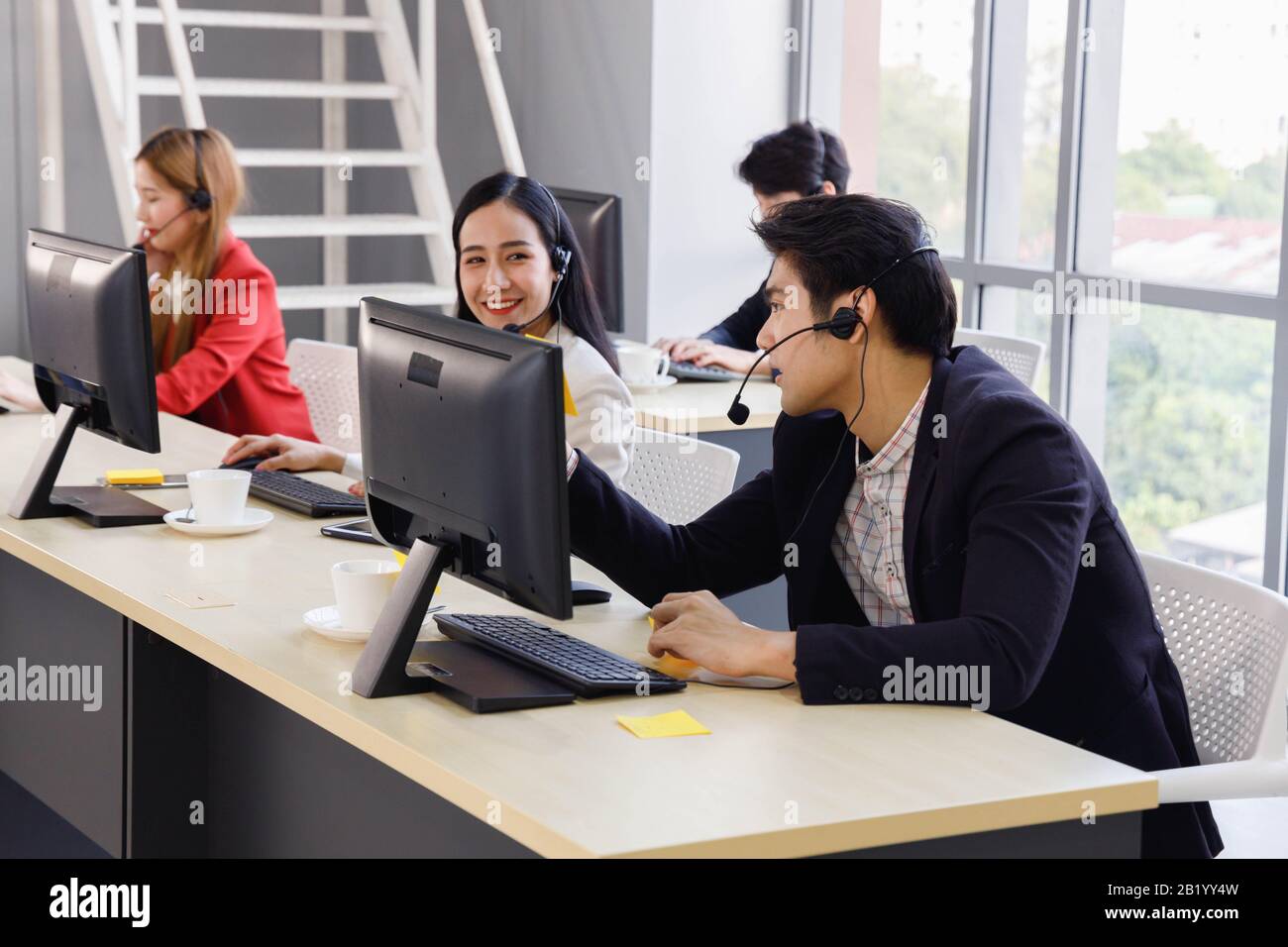 I dipendenti del call center asiatico lavorano insieme in ufficio. Concetto per servizio di assistenza clienti, ufficio, dipendente. Foto Stock