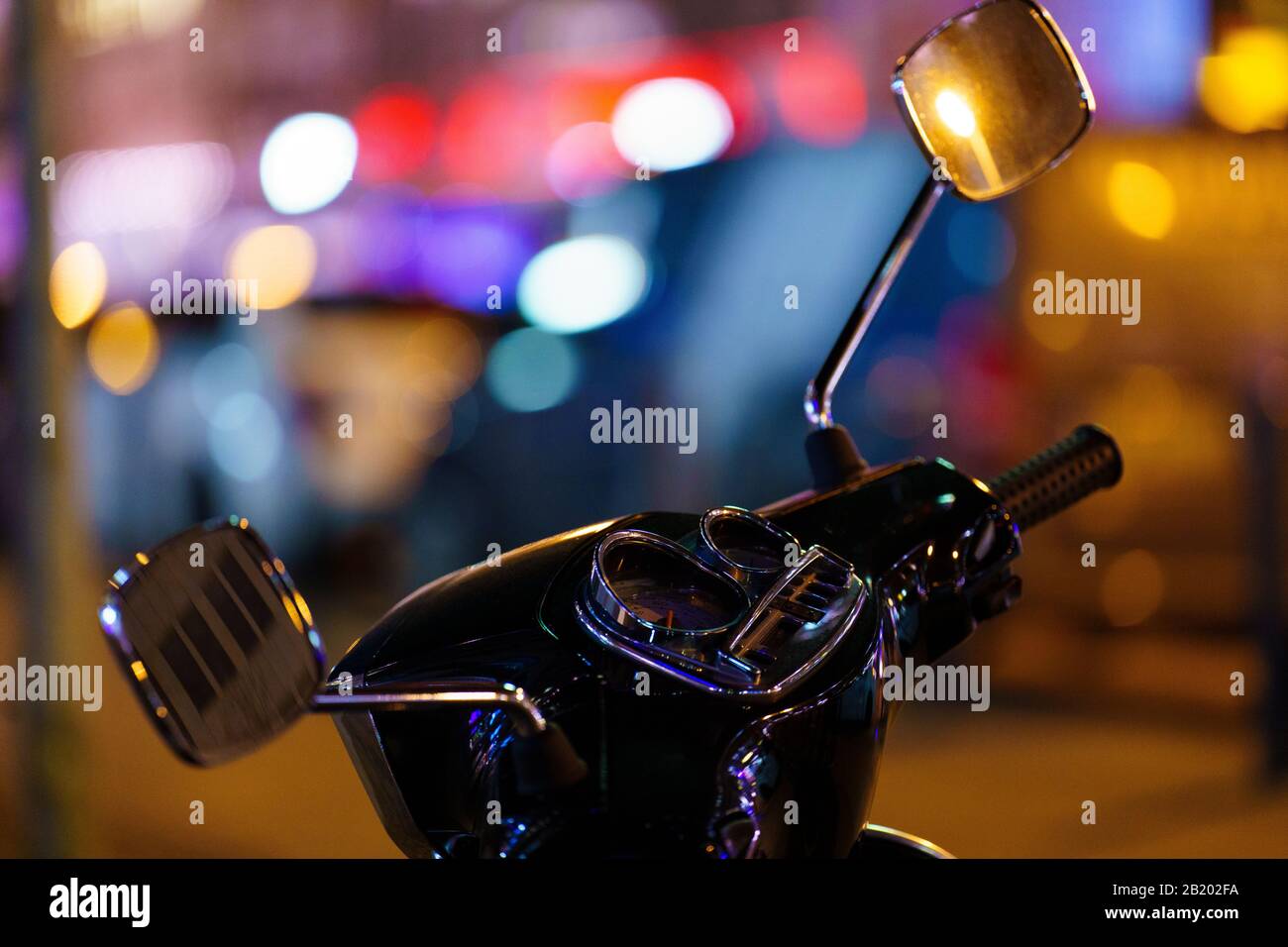 Fotografia notturna del cruscotto di un ciclo Vespa con le luci della città sullo sfondo Foto Stock