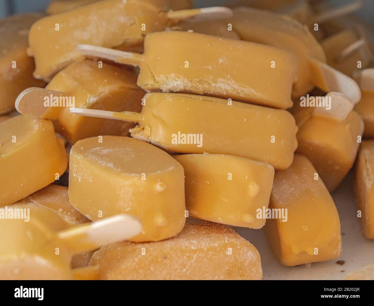 piccoli mini gelati arancioni con bastoncini Foto Stock