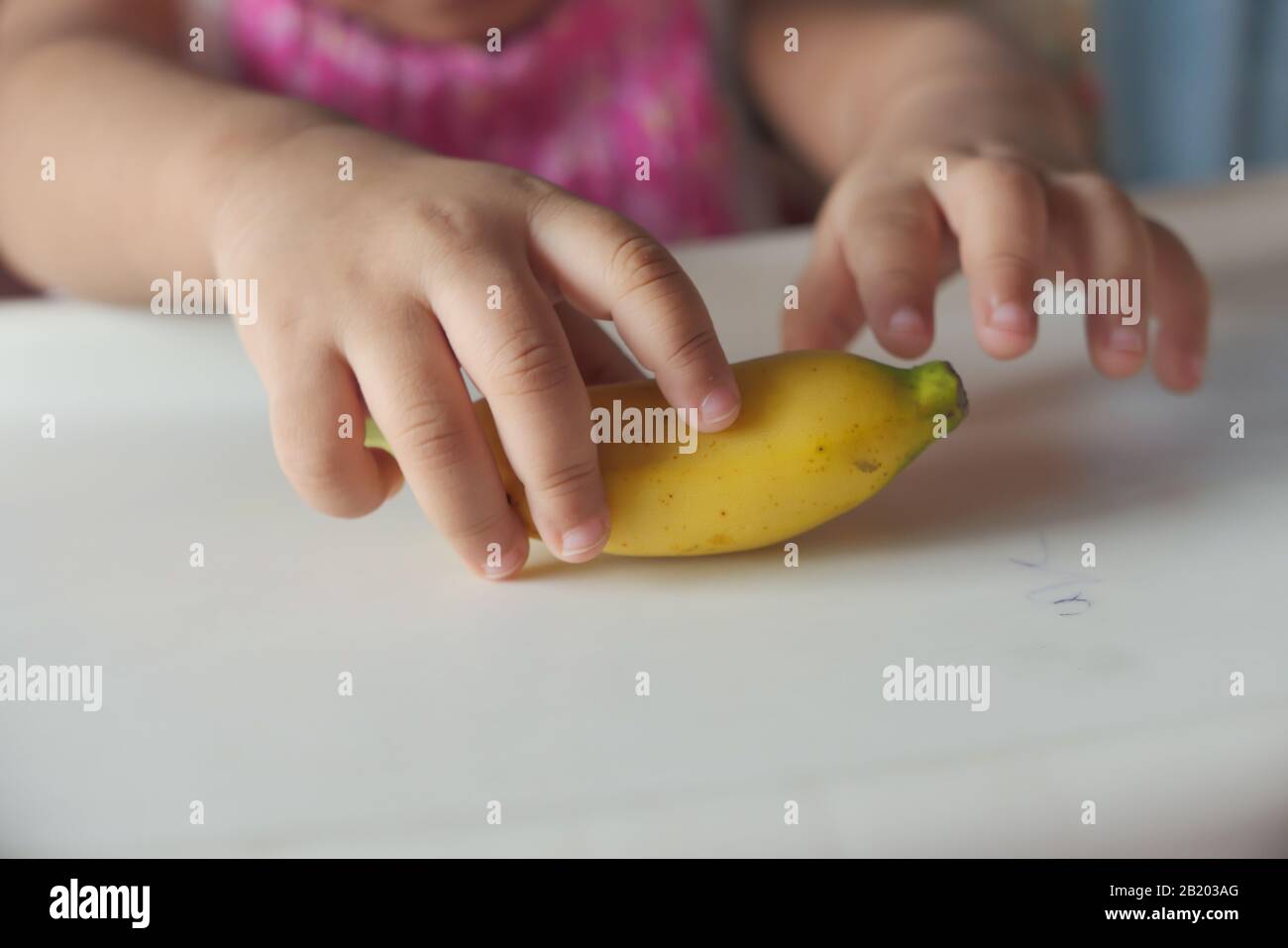 Primo piano di bambino mano che tiene la banana Foto Stock
