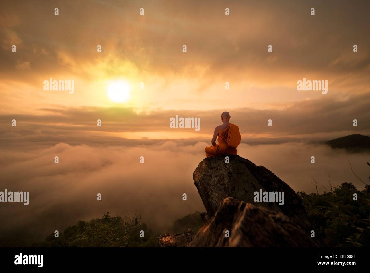 Monaco buddista in meditazione al bel tramonto o l'alba sullo sfondo di alta montagna Foto Stock