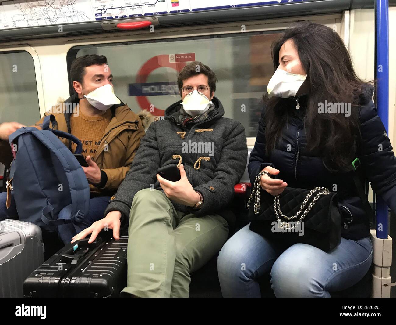 Persone che indossano maschere facciali sulla metropolitana di Londra, come il primo caso di coronavirus è stato confermato in Galles e altri due sono stati identificati in Inghilterra - portando il numero totale nel Regno Unito a 19. Foto Stock