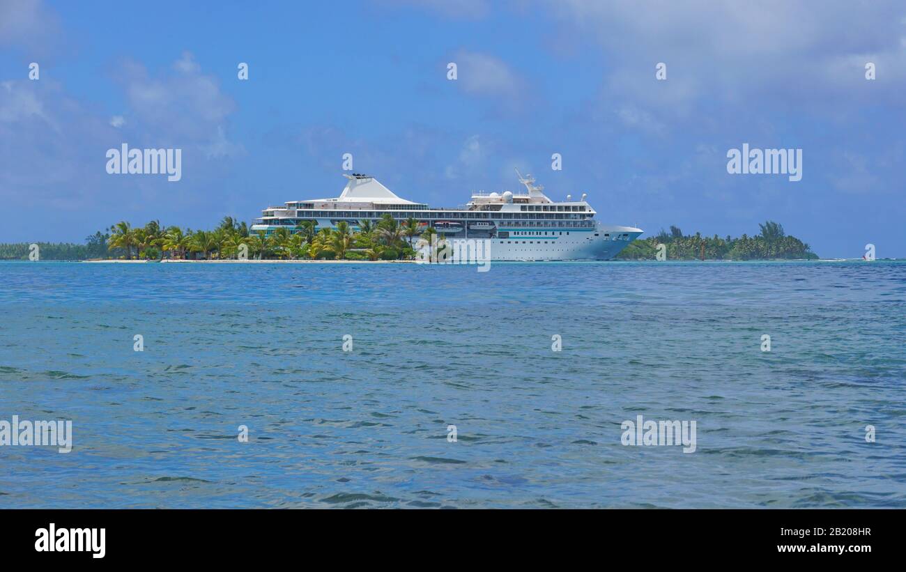 Piccola isola tropicale con una nave da crociera, oceano Pacifico meridionale, Polinesia Francese, Huahine Foto Stock