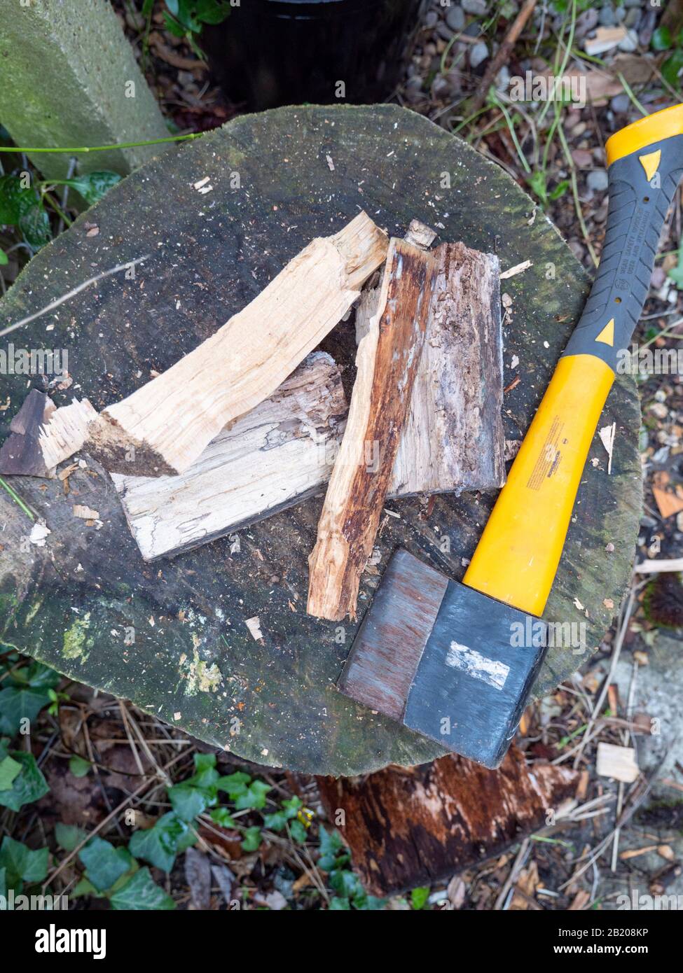 Un'ascia su un blocco di chopping con legno di accensione tritato pronto a bruciare sul fuoco domestico per il riscaldamento. Foto Stock