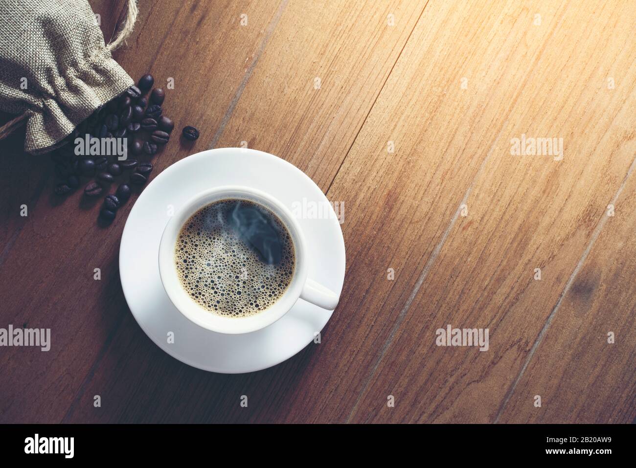 tazza di caffè bianco e chicchi di caffè su sfondo di legno. Vista dall'alto. Foto Stock