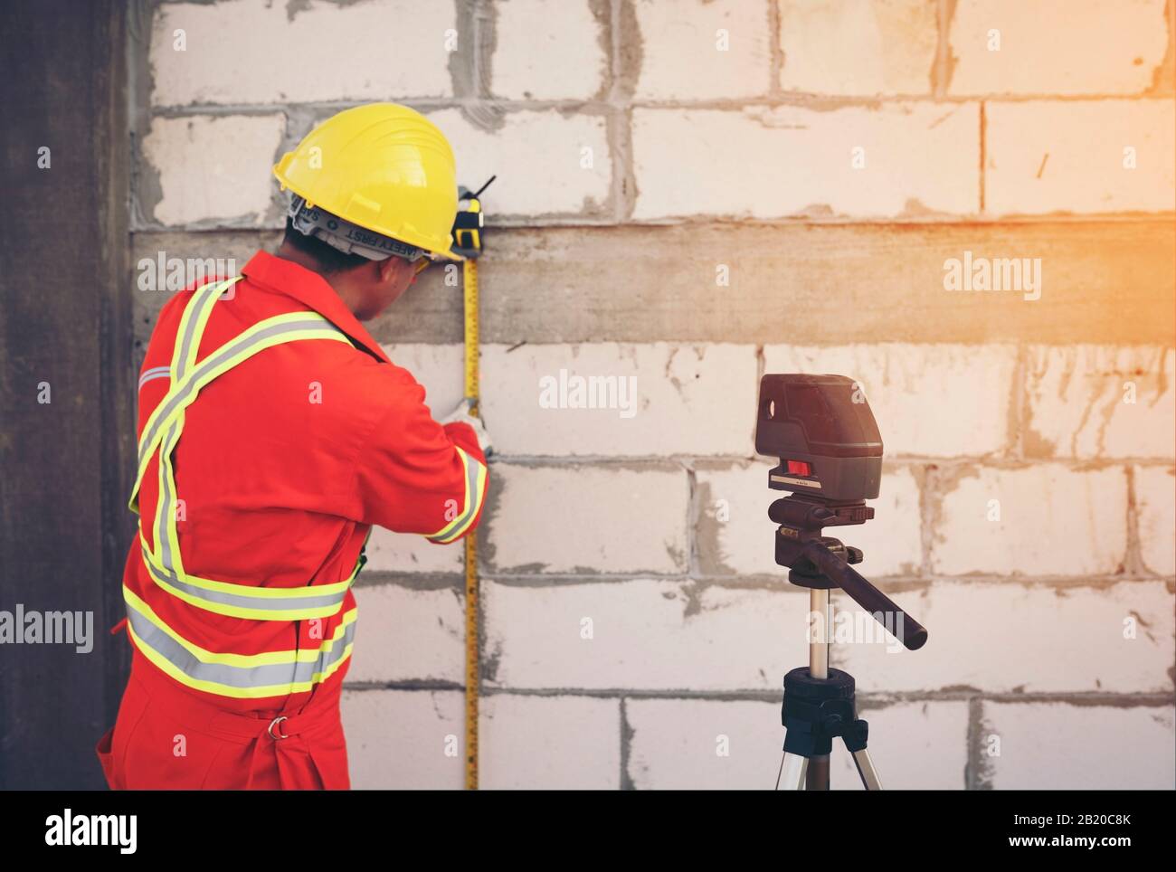 Tecnico con livello di misurazione laser durante il lavoro Foto Stock