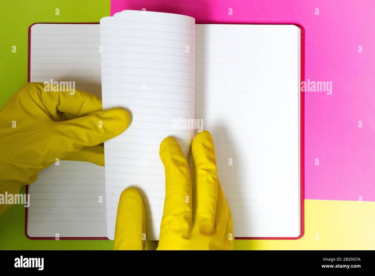 Puntare il dito con i guanti verso una pagina vuota del caricatore. Sfondo rosa e giallo brillante. Pericolo Foto Stock