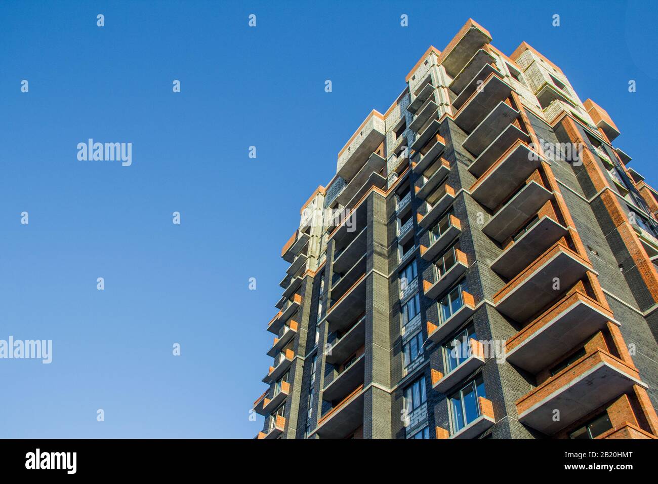 Costruzione di un nuovo edificio residenziale su sfondo blu cielo alla luce del sole che sorge. La tonalità del cielo è classica blu. Foto Stock