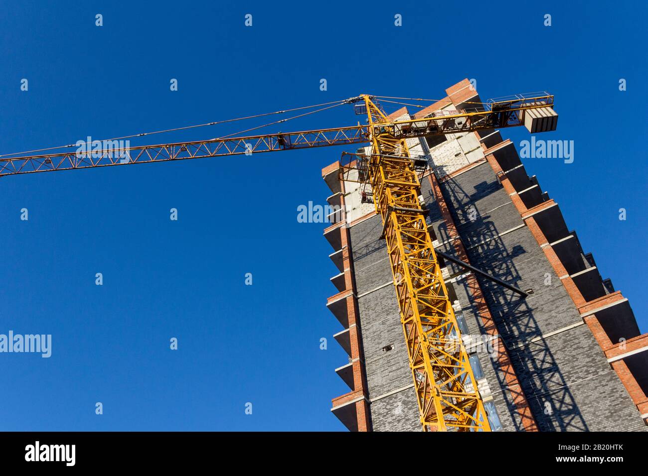 Costruzione di un nuovo edificio residenziale su sfondo blu cielo alla luce del sole che sorge. La tonalità del cielo è classica blu. Foto Stock