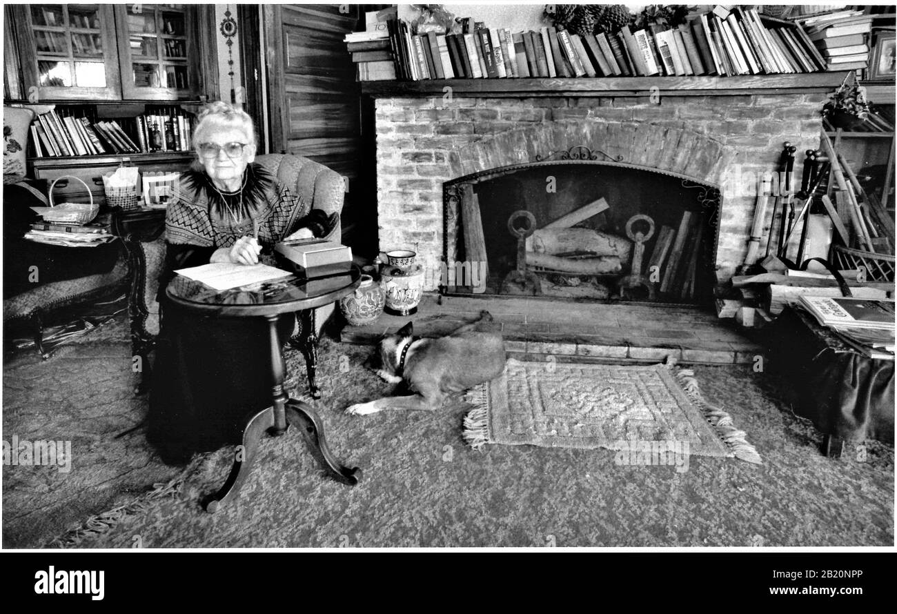 Donna anziana che è un poeta scrittore a Los Angeles siede nel suo soggiorno con i suoi libri Foto Stock