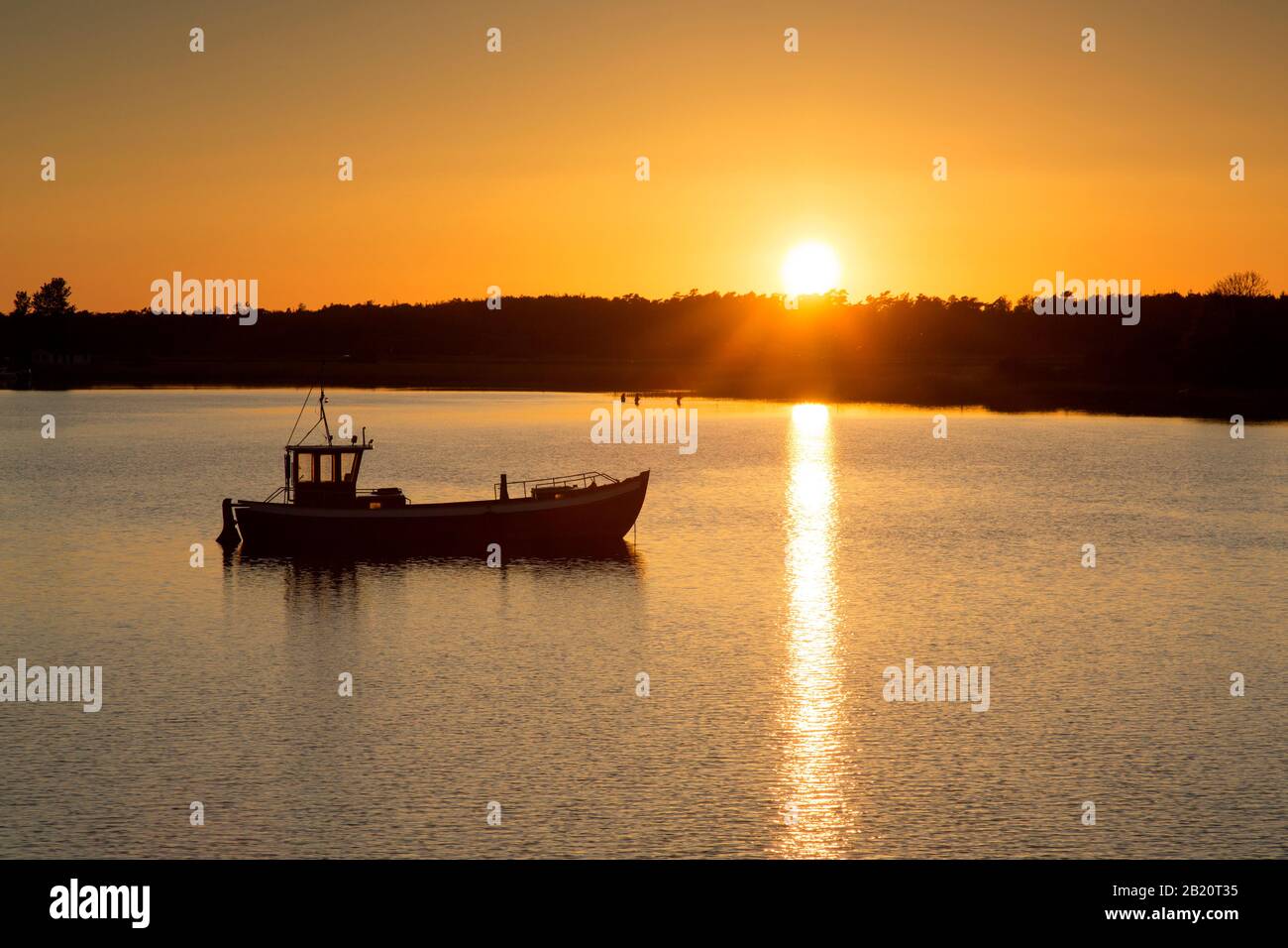 Imbarcazione da pesca silhouette contro il tramonto, isola di Ummanz, comune nel distretto di Vorpommern-Rügen nel Mecklenburg-Vorpommern, Germania Foto Stock