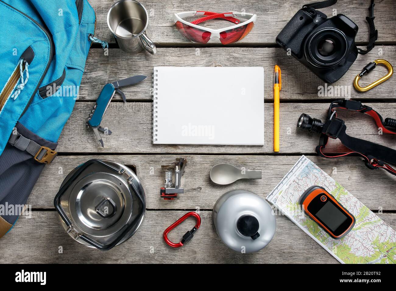 Attrezzature turistiche per viaggi e turismo su un pavimento di legno chiaro con uno spazio vuoto nel mezzo. Carta, coltello, corda, carabina, torcia elettrica, scarpe, GPS Foto Stock