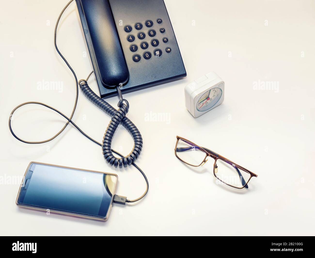 vecchia e nuova tecnologia su un comodino accanto a un bicchiere una sveglia Foto Stock