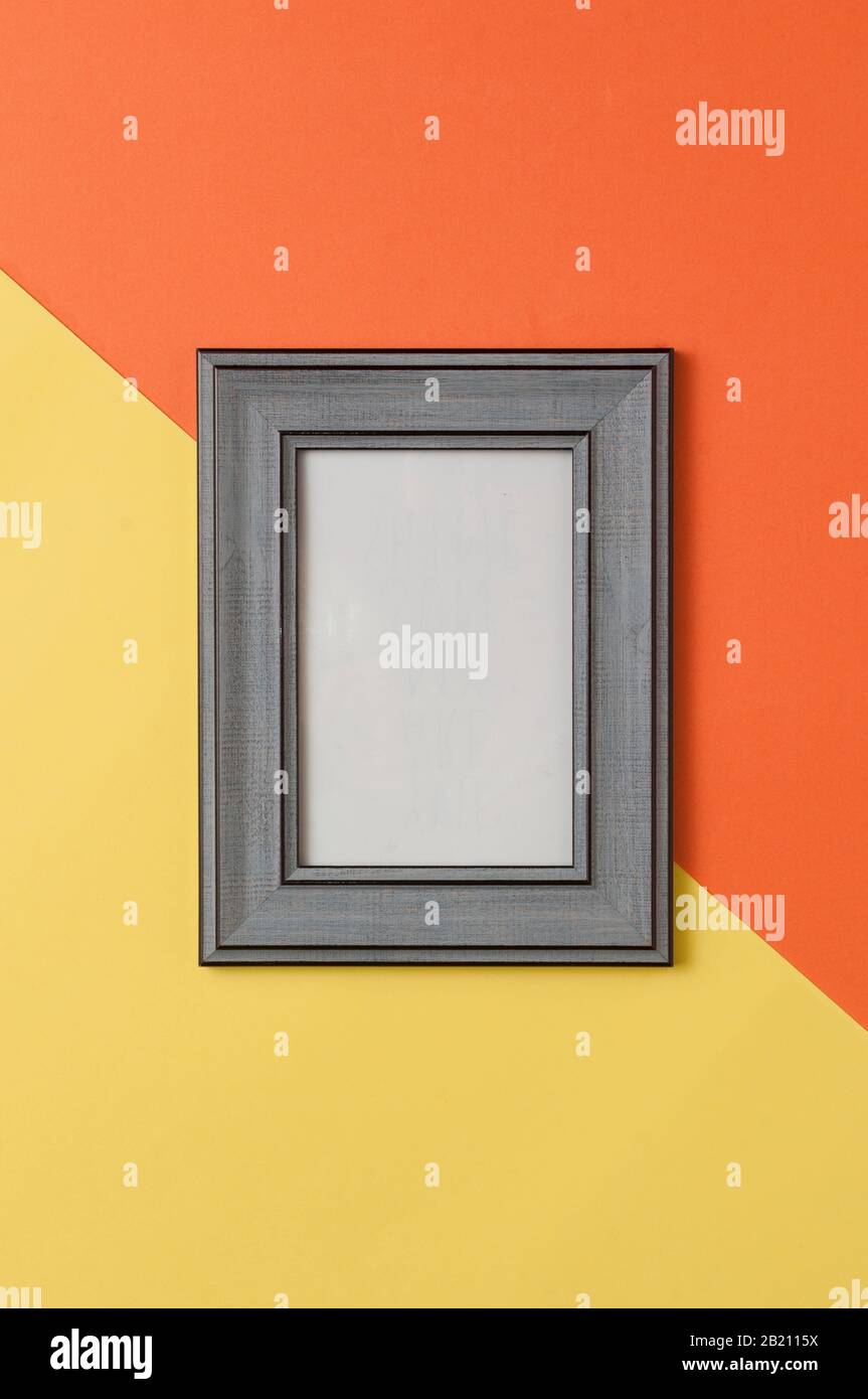 Cornice fotografica in legno grigio su sfondo giallo geometrico e arancione Foto Stock