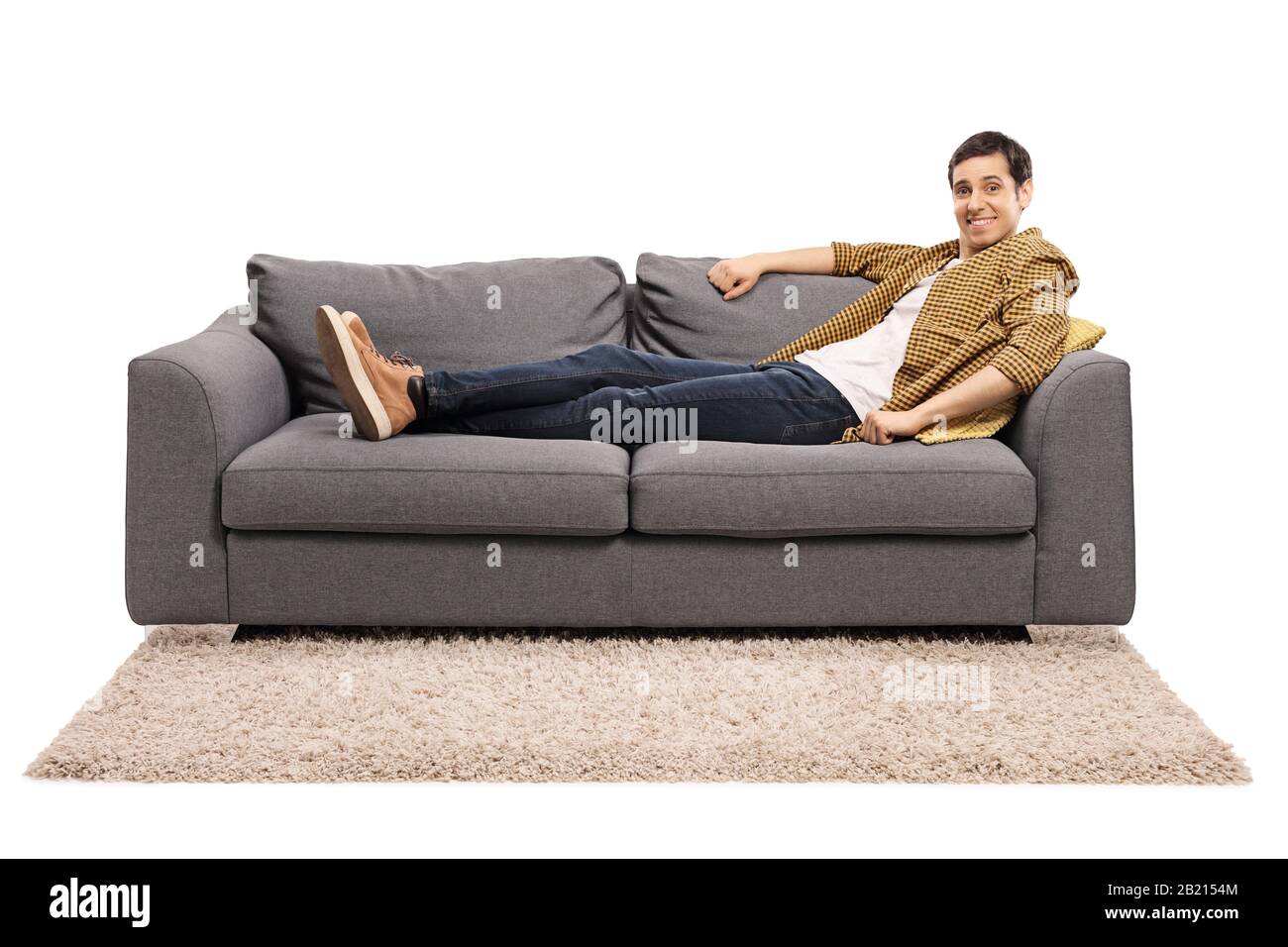 Giovane uomo seduto comodamente su un divano isolato su sfondo bianco Foto Stock