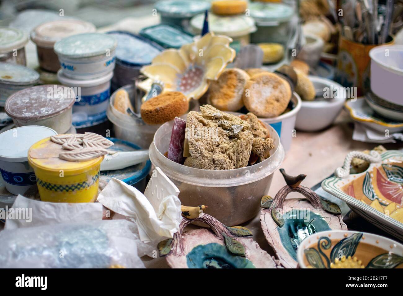 Spazzole, spugne e contenitori di smalti ceramici sono tutti parte di questa vita ancora in un negozio di ceramica occupato Foto Stock