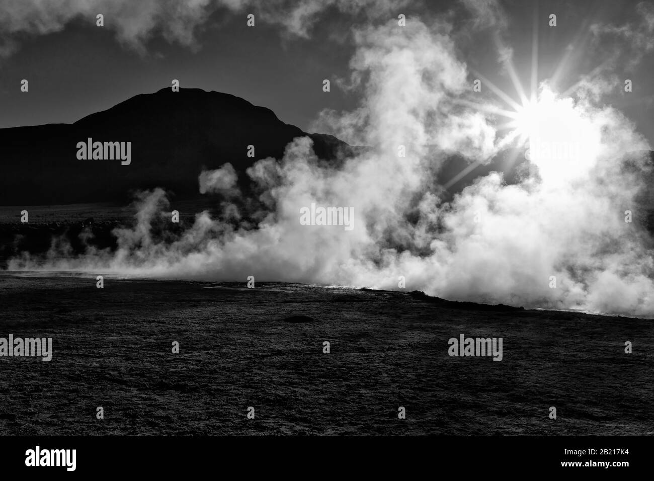 Sole che risplendente attraverso il vapore all'alba, El Tatio Geyser Field, Ande Mountains, Altiplano, Atacama Desert, Antofagasta, Cile, bianco e nero Foto Stock