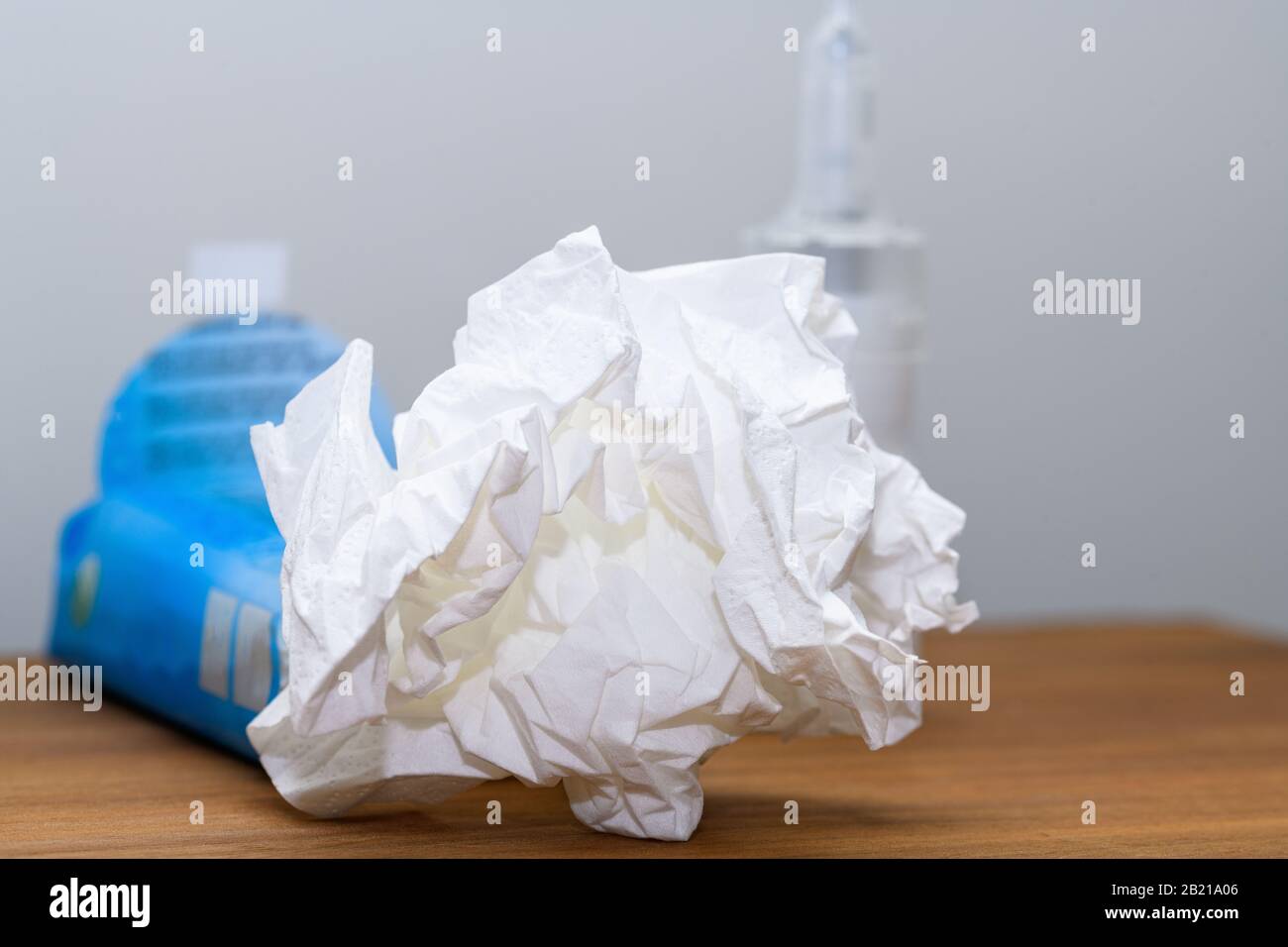 Primo piano del tessuto di carta e spray nasale su un comodino utilizzato durante raffreddore, influenza o virus. Concetto per le condizioni mediche all'interno di casa. Foto Stock