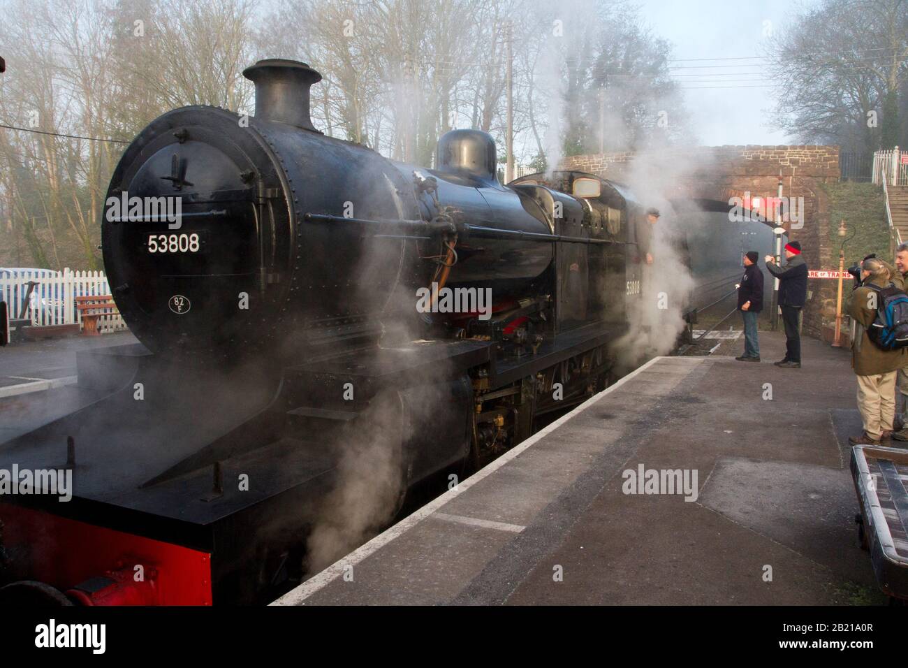 Un treno a vapore funzionante alla piattaforma presso la stazione di Bishops Lydeard sulla linea ferroviaria West Somerset con appassionati di treno che chiacchierano con l'autista Foto Stock