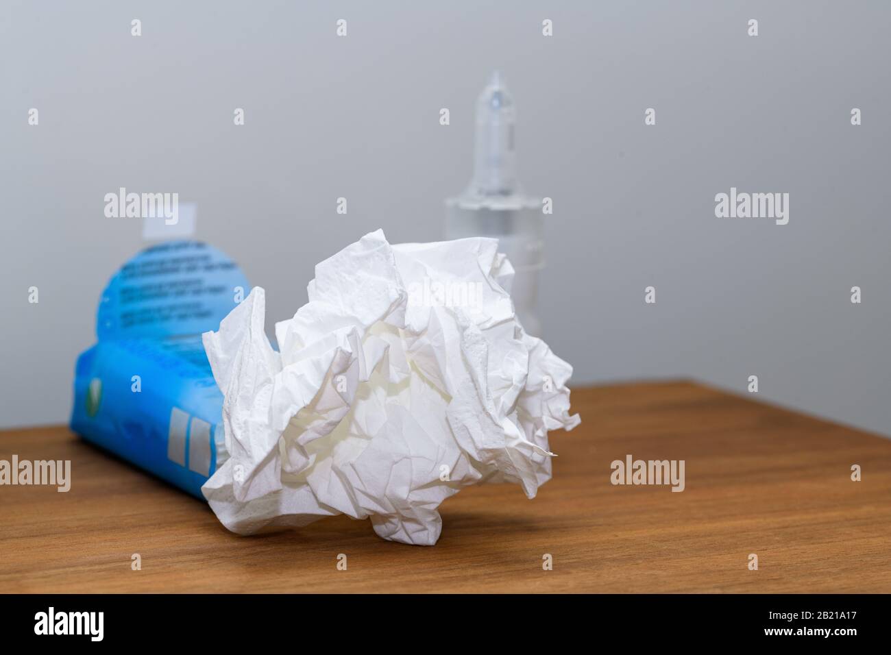 Carta tissue e spray nasale su un comodino utilizzato durante raffreddore, influenza o virus. Concetto per le condizioni mediche all'interno di casa. Foto Stock