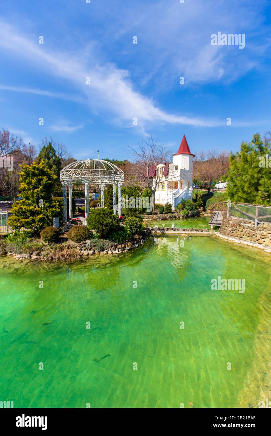 Lago con trote in montagna. Allevamento di trote. C'è una fontana nel lago. Vicino all'edificio di un ristorante e di un hotel Foto Stock